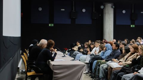 Cinefórum No Other Land con una mesa delante con 3 personas y el público en las sillas